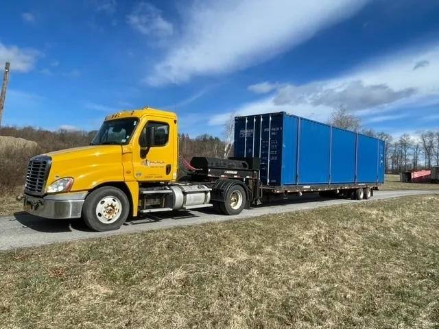 A yellow truck is pulling a blue trailer.